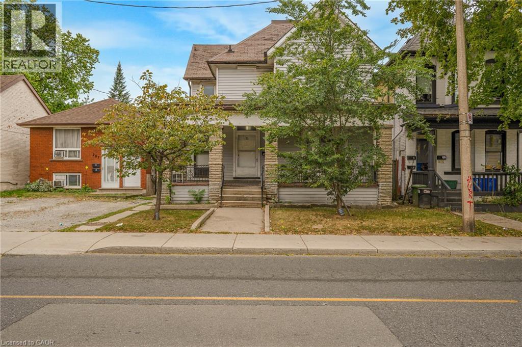 Property featuring a stone and siding exterior, front entry with transom window, and a mature tree in the front yard - 211 Wentworth Street N, Hamilton, ON