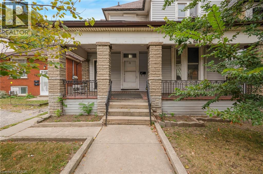Stone-clad porch columns, concrete steps with metal railings, and a prominent front entrance - 211 Wentworth Street N, Hamilton, ON