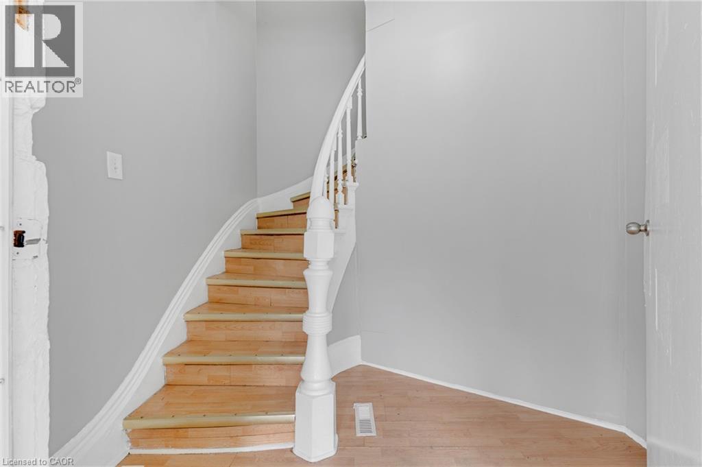 Curved wooden staircase featuring white balusters and a substantial newel post - 211 Wentworth Street N, Hamilton, ON