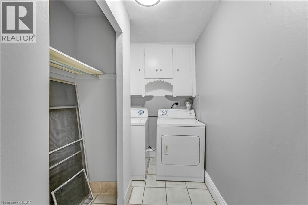Laundry area featuring overhead cabinetry, tile flooring, and a built-in shelf - 211 Wentworth Street N, Hamilton, ON