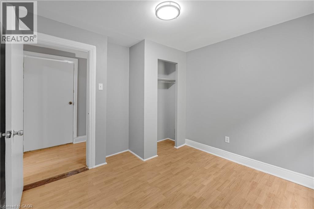 Recessed closet with shelving and hanging rod, wood-finish flooring, flush mount ceiling light fixture, and freshly painted gray walls - 211 Wentworth Street N, Hamilton, ON