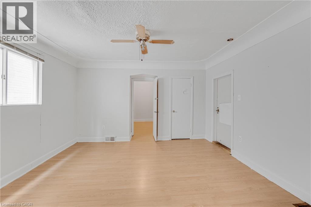 Light wood-finish flooring, white walls, arched doorway, and overhead ceiling fan - 211 Wentworth Street N, Hamilton, ON
