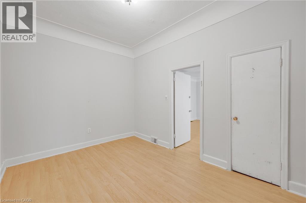 Light wood-finish flooring with white baseboards - 211 Wentworth Street N, Hamilton, ON