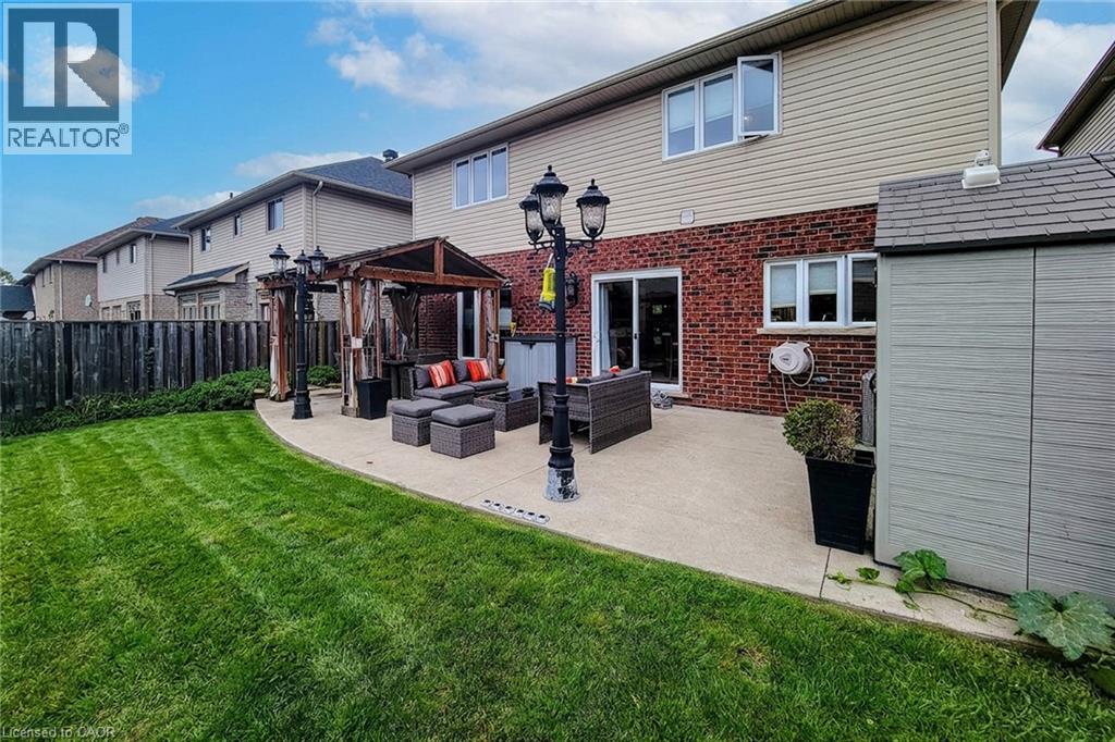 Expansive backyard featuring a manicured lawn, concrete patio, and a wood pergola - 214 Cloverleaf Drive, Ancaster, ON