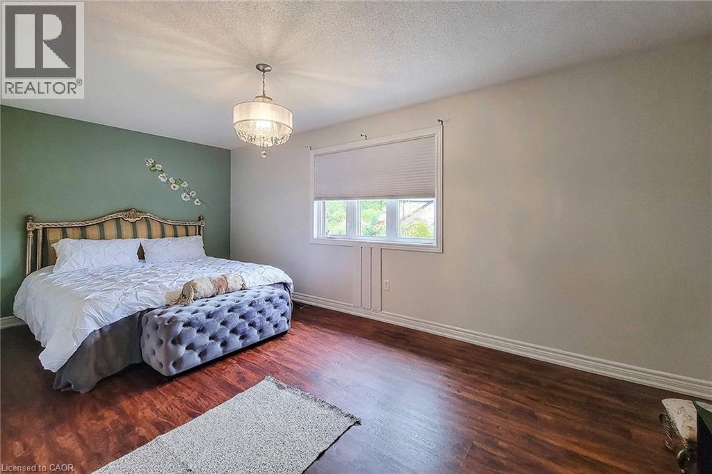 Wood-finish flooring, single window with blinds, decorative light fixture, painted accent wall, and white trim - 214 Cloverleaf Drive, Ancaster, ON