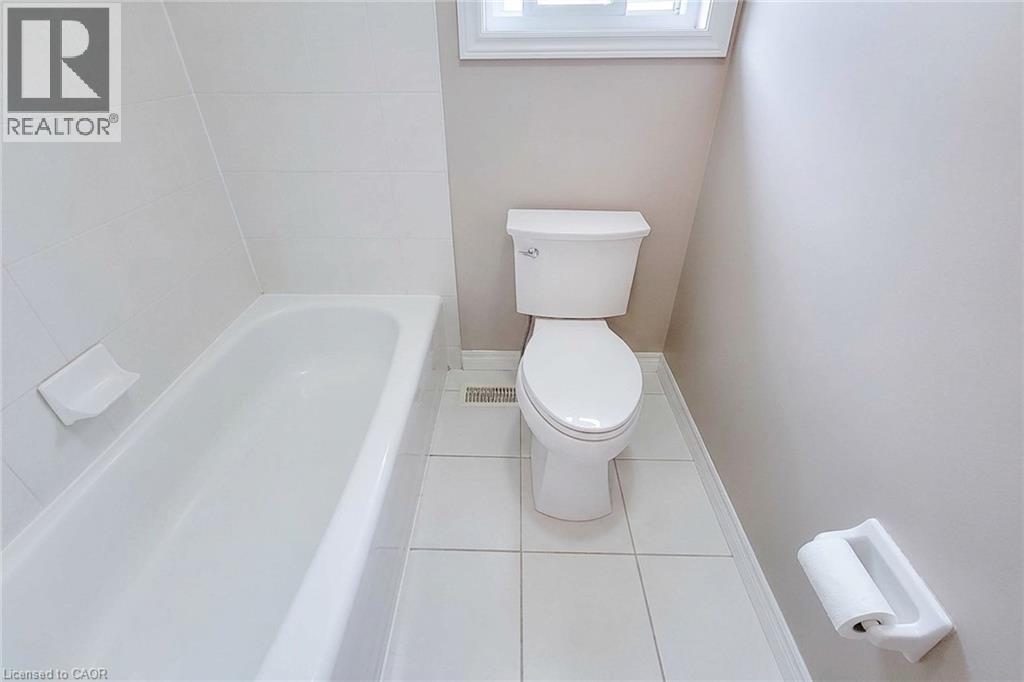 White ceramic tile flooring, bathtub with white tile surround, and a window with natural light - 214 Cloverleaf Drive, Ancaster, ON