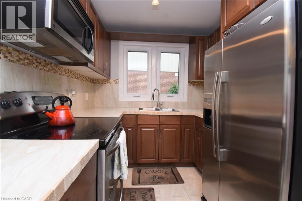 Kitchen featuring wood cabinetry, stainless steel appliances, a tile backsplash, and a window above the sink - 154 Ewen Road, Hamilton, ON