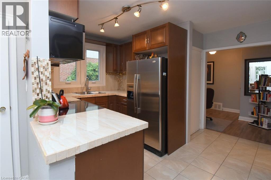 Kitchen featuring wood cabinetry, stainless steel appliances, a light-toned tile backsplash, and track lighting - 154 Ewen Road, Hamilton, ON