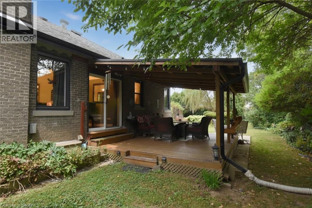 Expansive wood-finish deck with a covered area, directly accessible via sliding glass doors - 154 Ewen Road, Hamilton, ON