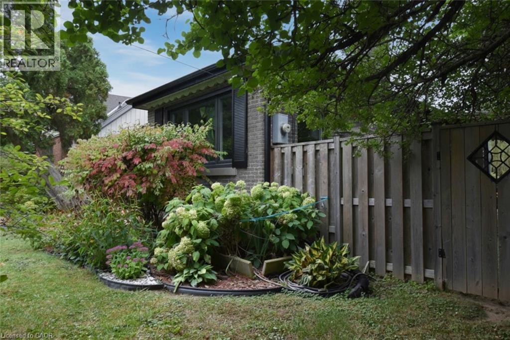 Brick exterior, window with awning, mature landscaping, wood privacy fence, decorative gate insert - 154 Ewen Road, Hamilton, ON
