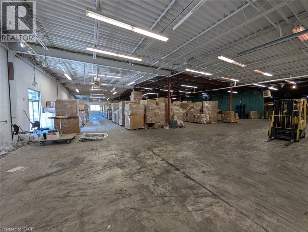 Expansive concrete flooring with a high ceiling, visible structural beams, and ample overhead lighting - 97 Ardelt Avenue, Kitchener, ON