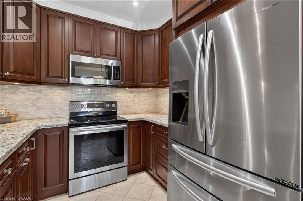 Kitchen featuring dark wood cabinetry, light granite countertops, and a mosaic tile backsplash - 1347 Brookstar Drive, Oakville, ON