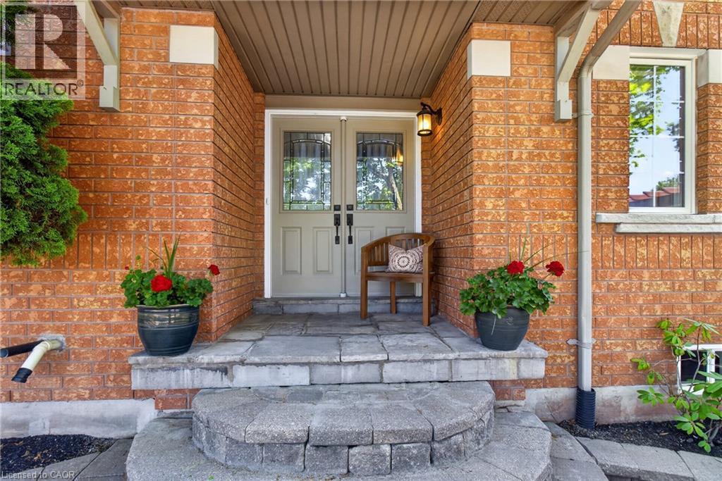 Brick exterior featuring a covered entry, double entry doors with decorative glass, and a stone paver pathway - 1347 Brookstar Drive, Oakville, ON