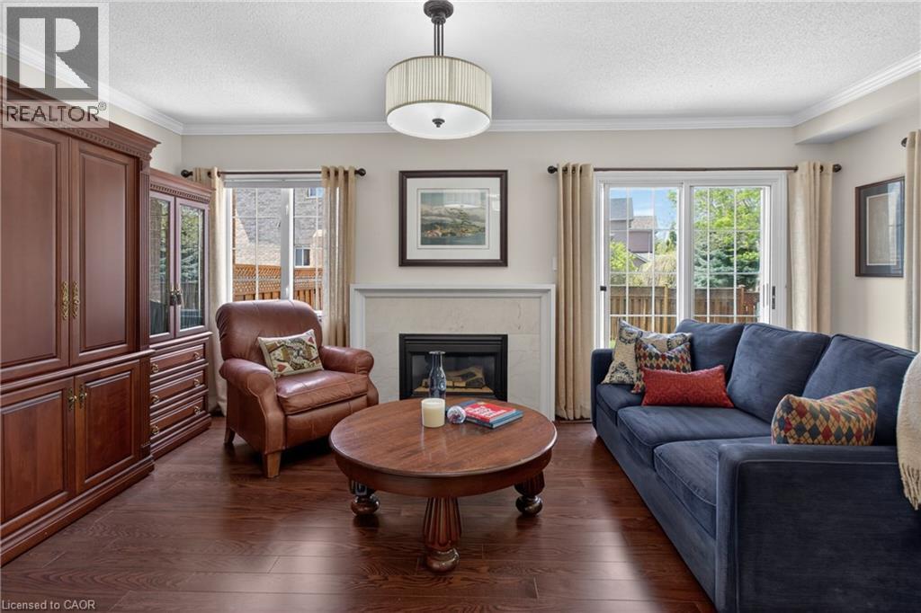 Living area featuring rich wood-finish flooring, a white mantel fireplace, crown molding, and a sliding glass door to the exterior - 1347 Brookstar Drive, Oakville, ON