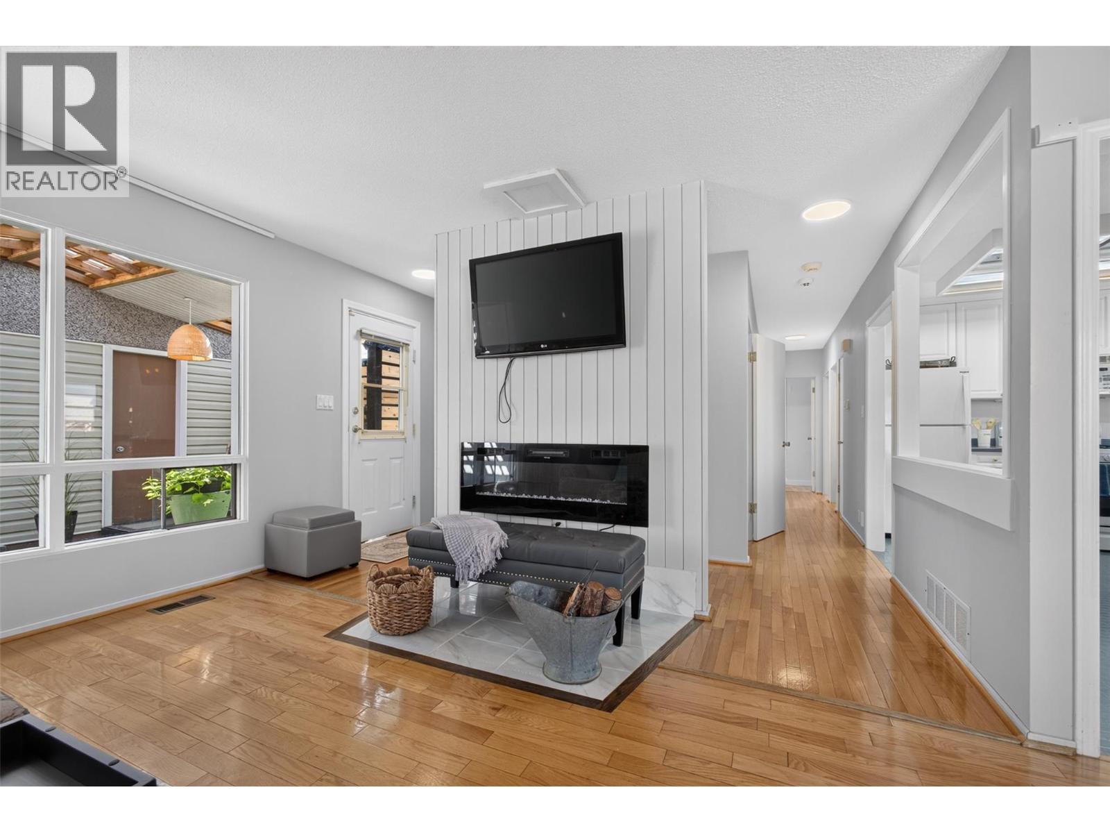 Bright and inviting living room featuring an electric fireplace and direct access to the outdoor patio, creating an easy flow between indoor and outdoor living. - 1261 Lawson Avenue, Kelowna, BC