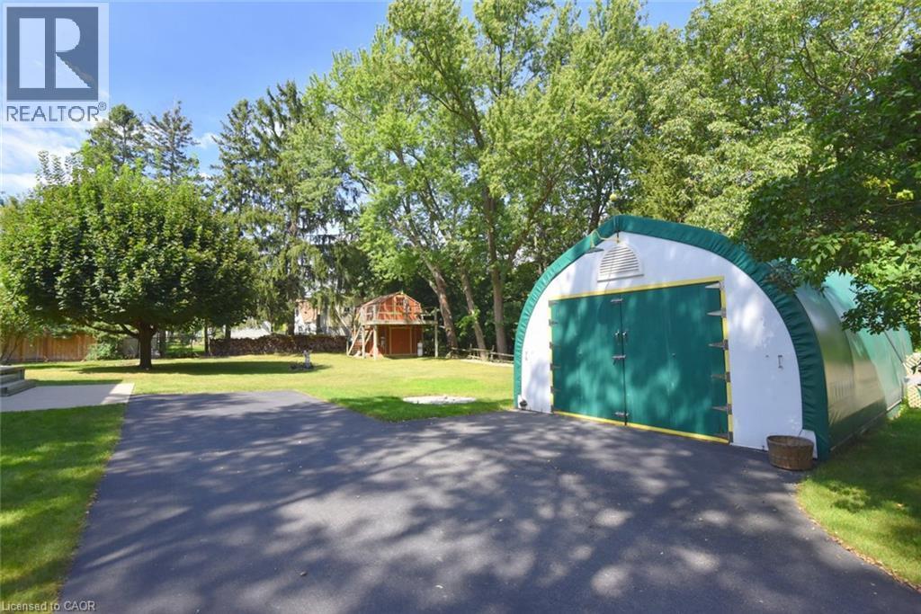 Paved driveway leading to a large freestanding storage structure with green doors - 781 Oakdale Avenue, Burlington, ON