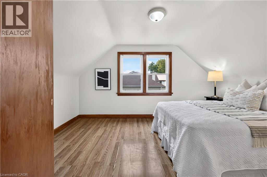 Attic space with wood-finish flooring, white walls, and a window with wood trim - 176 Avalon Place, Kitchener, ON