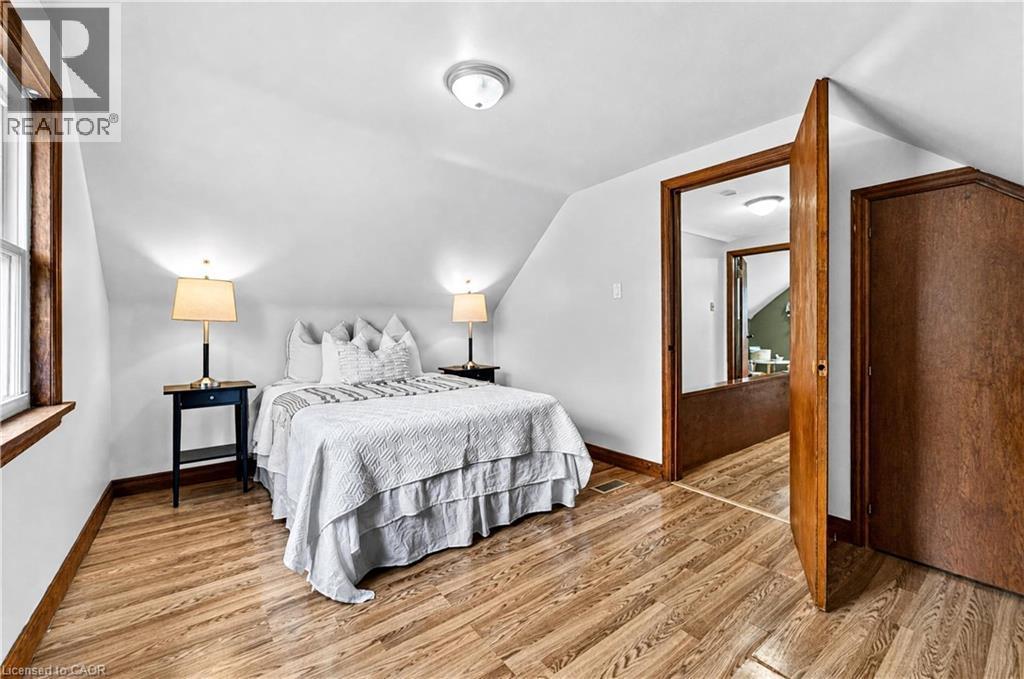 Wood-finish flooring, white walls, angled ceiling, wood trim, and a flush mount ceiling light - 176 Avalon Place, Kitchener, ON