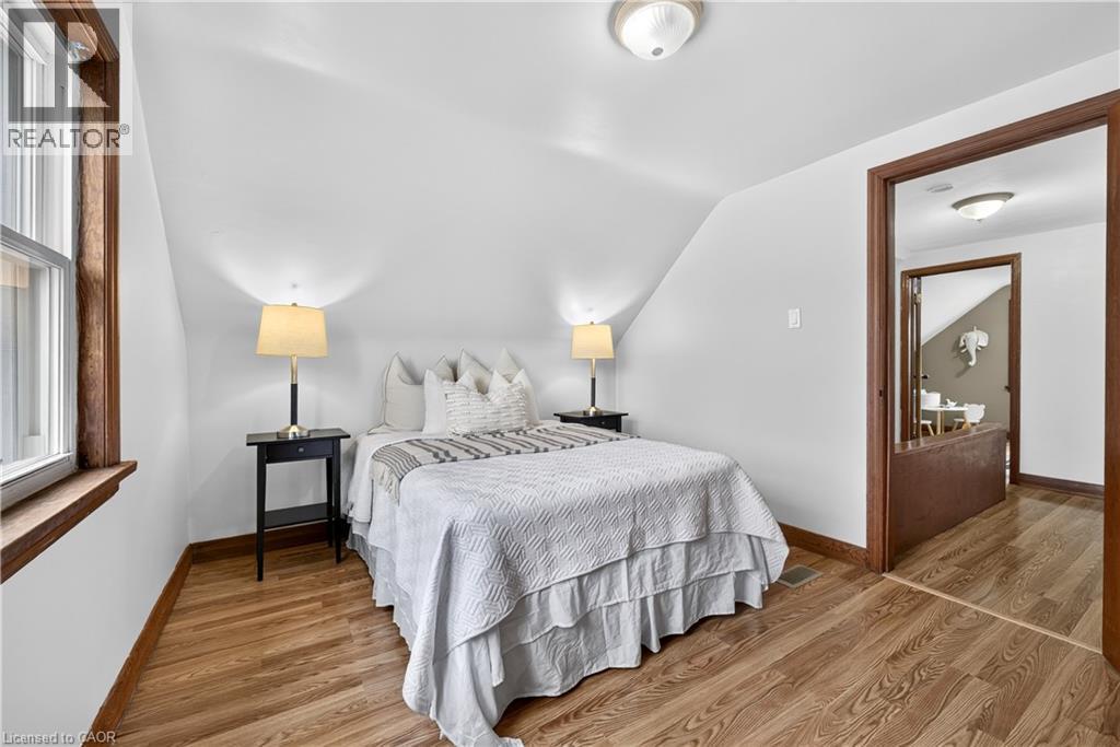 Sloped ceiling room featuring wood-finish flooring, white walls, and a window with wood trim - 176 Avalon Place, Kitchener, ON
