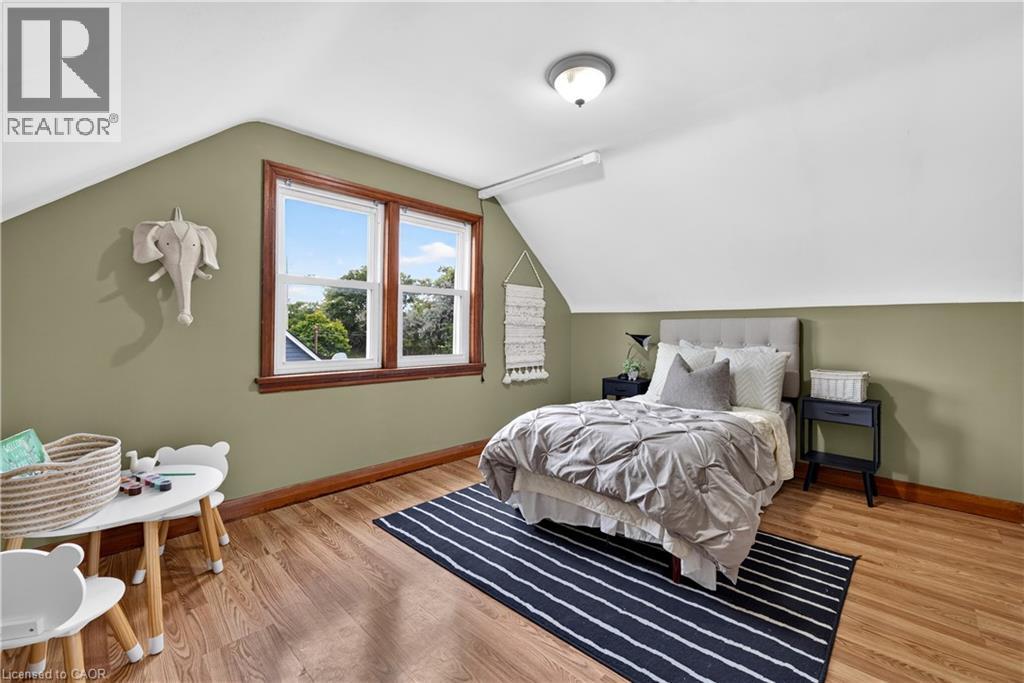Sloped white ceiling with recessed lighting, green wall accent, wood-finish flooring, and white-framed windows with natural wood trim - 176 Avalon Place, Kitchener, ON