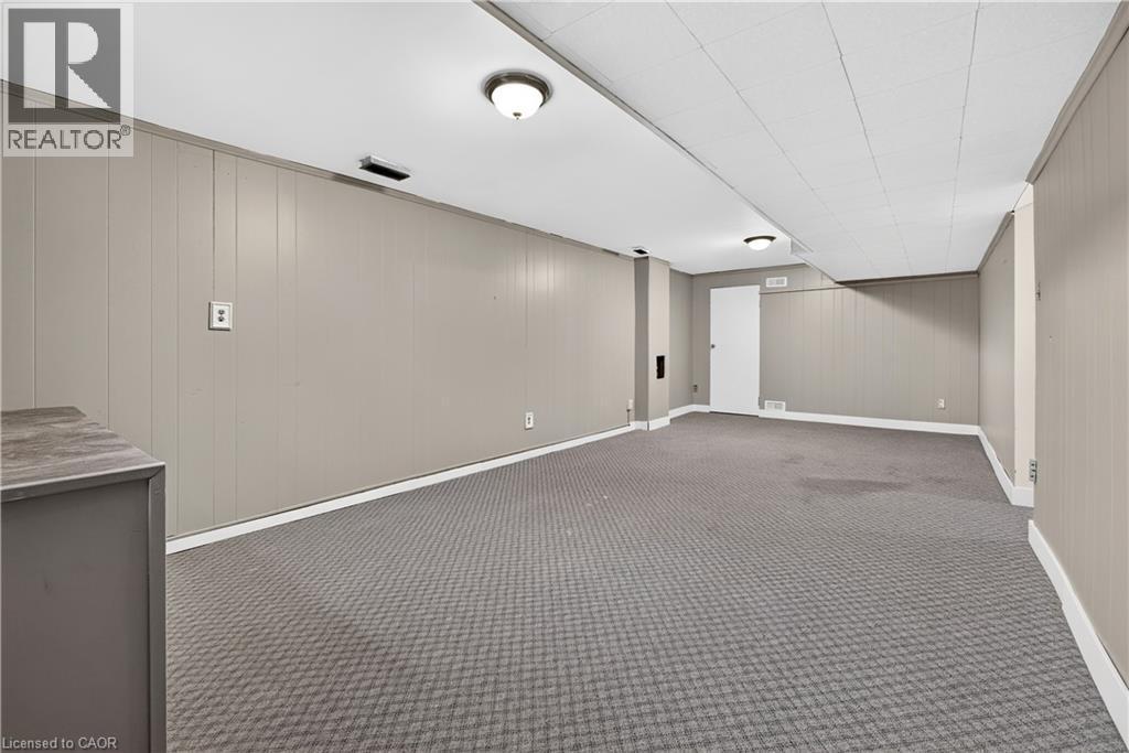 Expansive room featuring wall paneling, ceiling-mounted lighting, and carpet flooring - 176 Avalon Place, Kitchener, ON