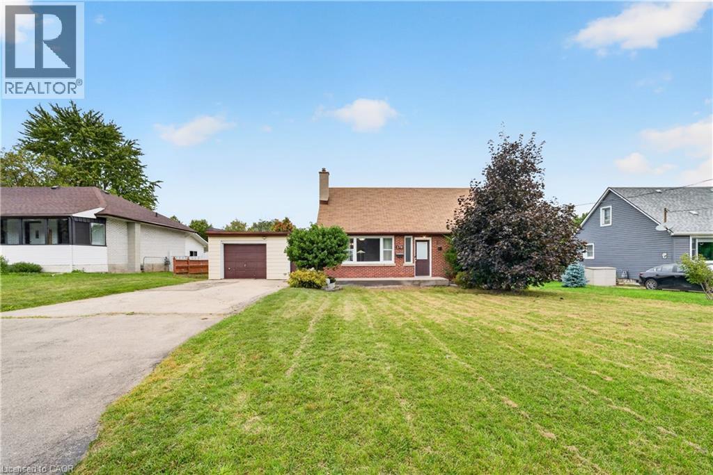 Brick facade residence with a pitched roof, front lawn, mature trees, an attached garage, and a paved driveway - 176 Avalon Place, Kitchener, ON
