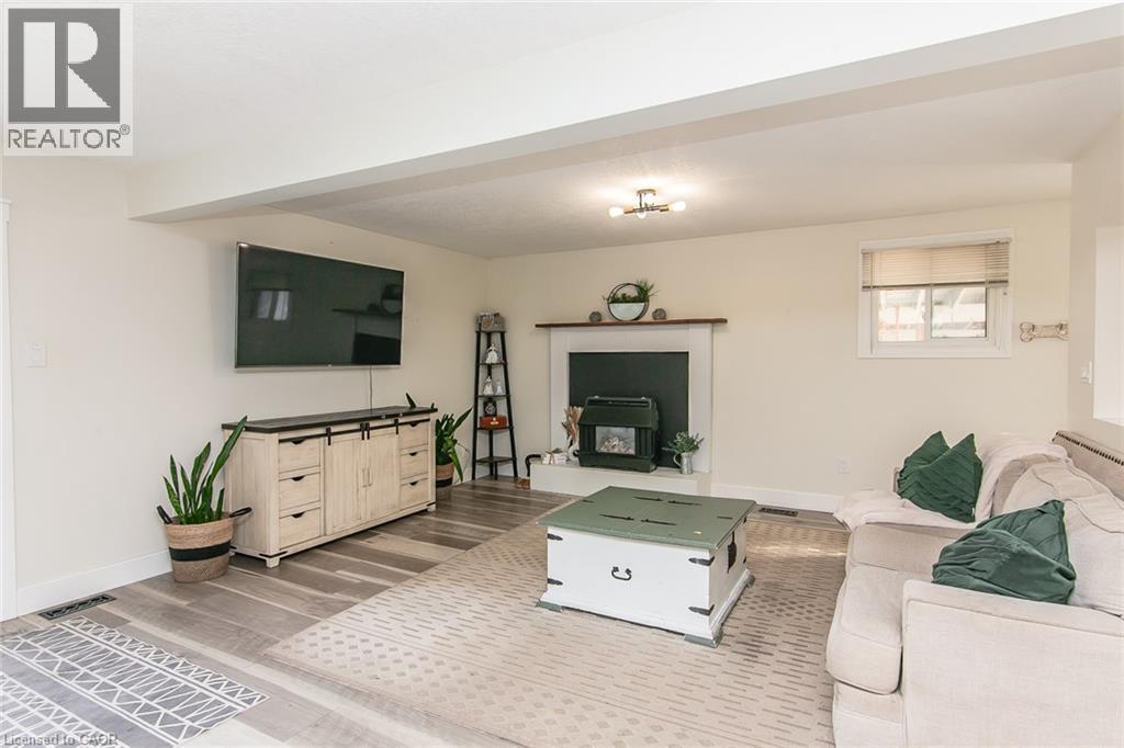 Spacious room featuring wood-finish flooring, a built-in fireplace, and overhead lighting - 393 Huron Street, New Hamburg, ON