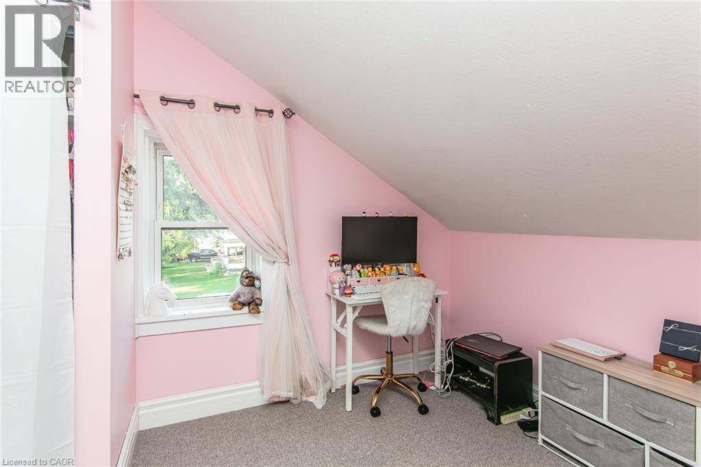 Sloped ceiling room featuring a double-hung window with exterior scenery, wall-to-wall carpeting, and painted walls - 393 Huron Street, New Hamburg, ON
