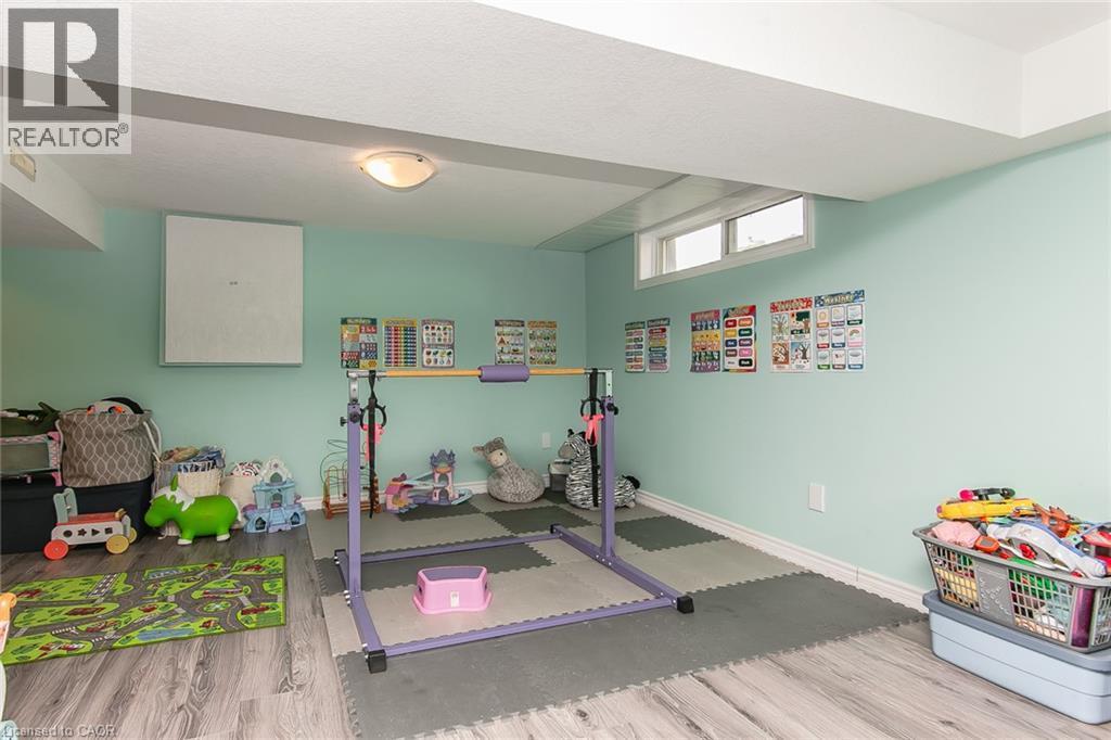 Finished lower level with wood-finish flooring, light fixture, and window - 393 Huron Street, New Hamburg, ON