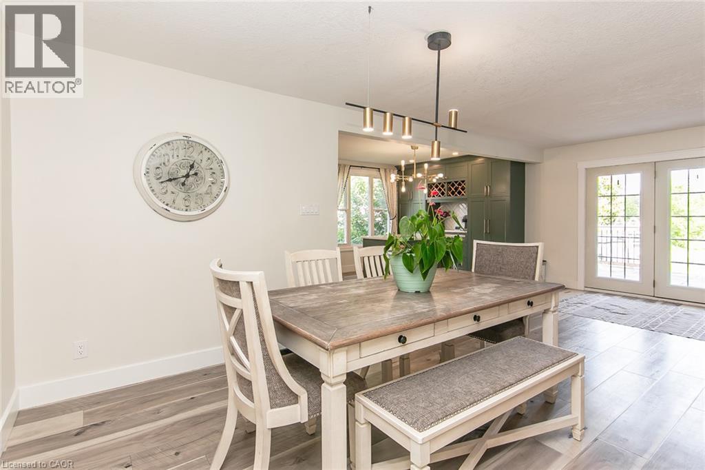 Wood-finish flooring, modern linear chandelier, and white French doors - 393 Huron Street, New Hamburg, ON