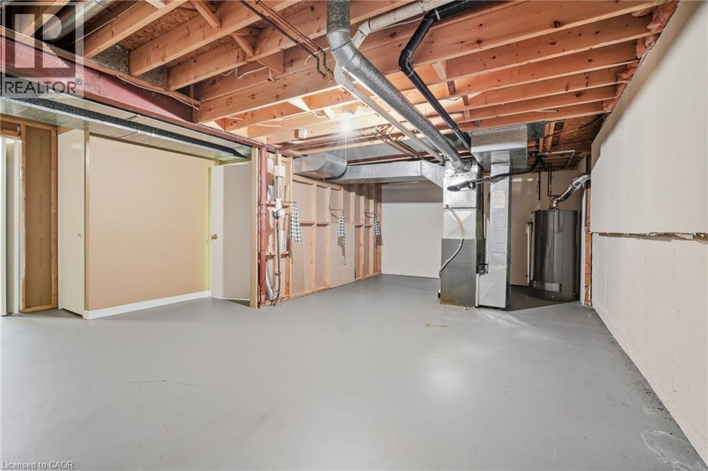 Spacious unfinished basement with exposed wooden ceiling joists, exposed ductwork, a water heater, and a furnace - 5 Michelle Drive, St. Catharines, ON