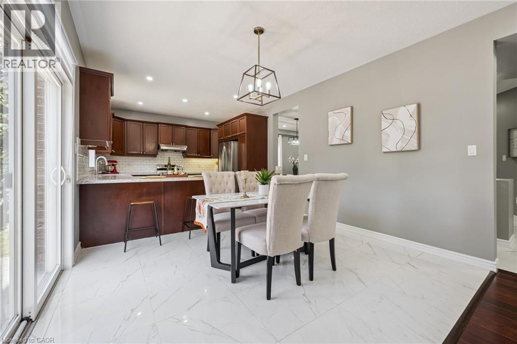 Kitchen featuring dark wood cabinetry, a subway tile backsplash, and stainless steel appliances - 154 Falconridge Drive, Kitchener, ON