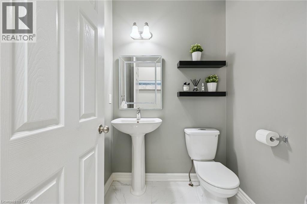 Pedestal sink with chrome faucet, wall-mounted mirror, and overhead vanity lighting - 154 Falconridge Drive, Kitchener, ON