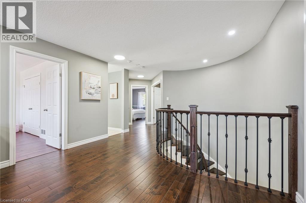 Hardwood flooring throughout, recessed lighting, white trim, and a curved staircase with wrought iron balusters - 154 Falconridge Drive, Kitchener, ON