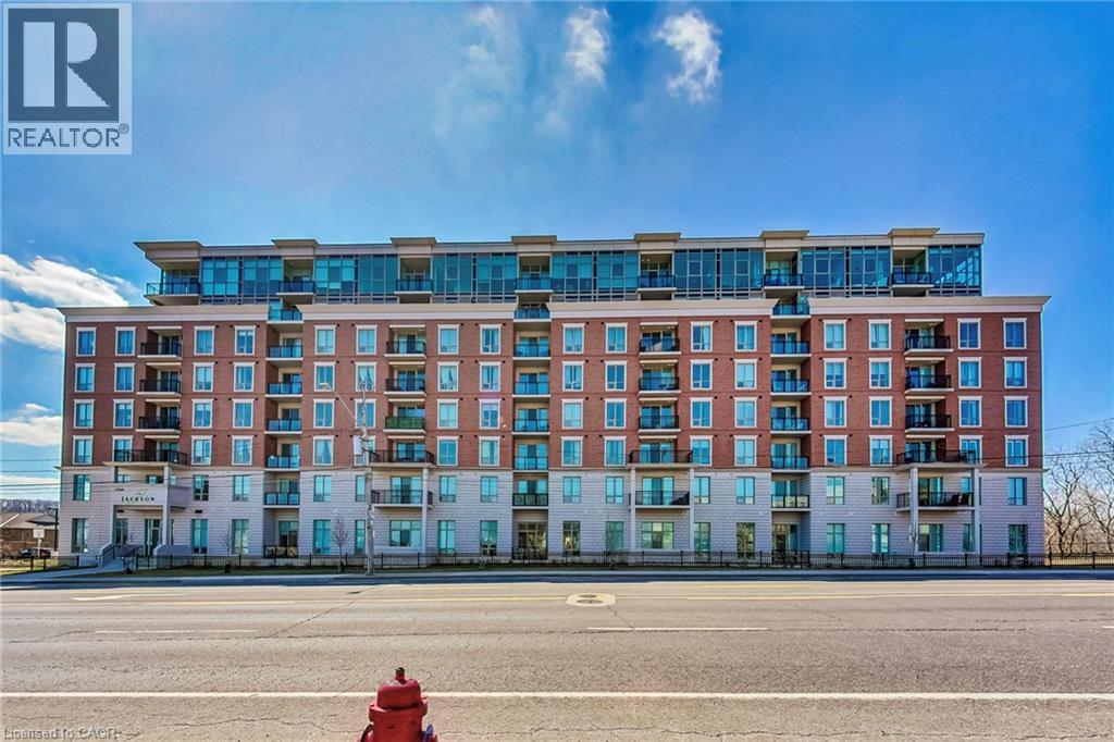 Brick facade building featuring multiple balconies, a ground-level entrance, and upper-level glass balconies - 2750 King Street E Unit# 103, Hamilton, ON