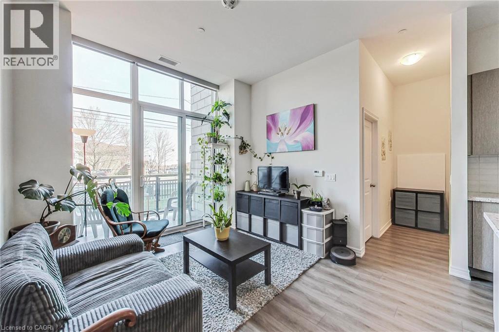 Floor-to-ceiling windows, balcony access, light wood-finish flooring, recessed lighting, and kitchen with light cabinetry - 2750 King Street E Unit# 103, Hamilton, ON