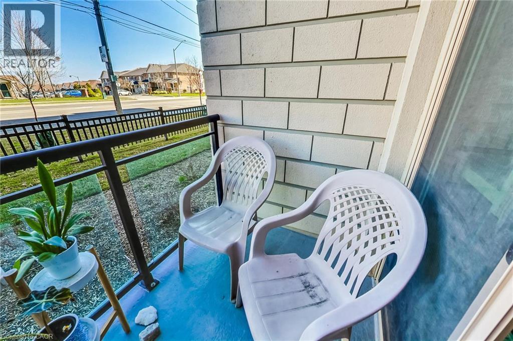 Balcony featuring a glass and metal railing, textured exterior siding, and a blue-painted floor - 2750 King Street E Unit# 103, Hamilton, ON