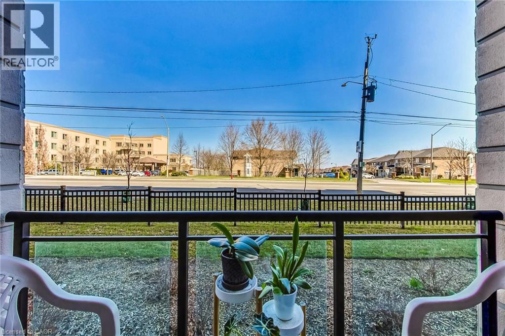 Balcony with metal and glass railing overlooking green space and an expansive roadway - 2750 King Street E Unit# 103, Hamilton, ON