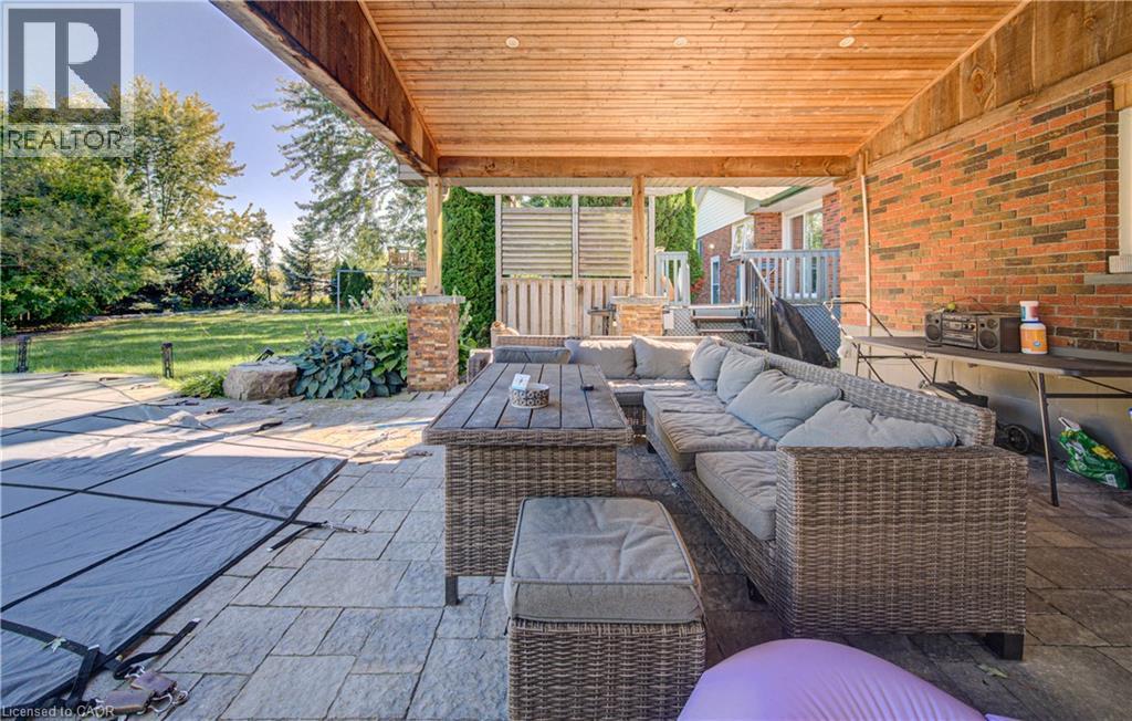 Covered patio with a wood-plank ceiling, brick exterior wall, and stone-finish flooring - 3160 Binbrook Road, Binbrook, ON