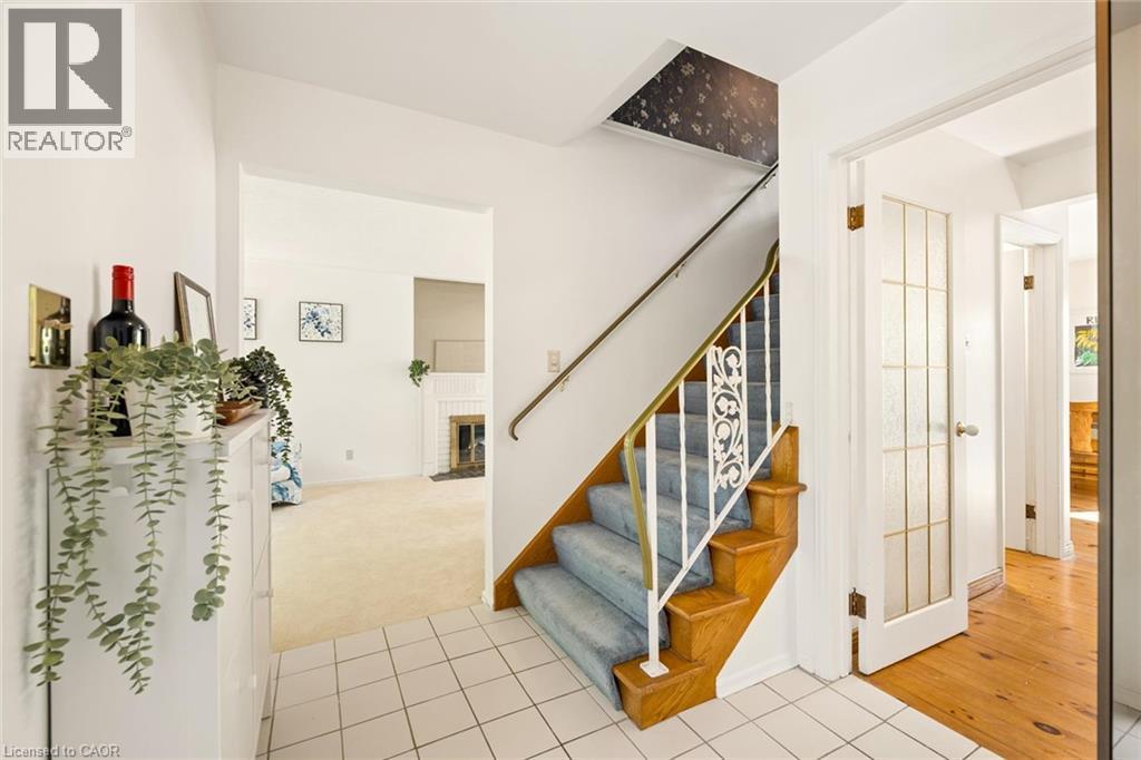 Tiled entryway with a wood staircase, carpeted treads, and decorative metal balusters - 351 Craigleith Drive, Waterloo, ON