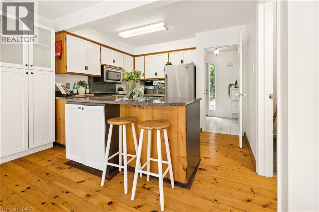 Kitchen featuring wood-finish flooring, wood cabinetry with white doors, an island with countertop, and stainless steel appliances - 351 Craigleith Drive, Waterloo, ON