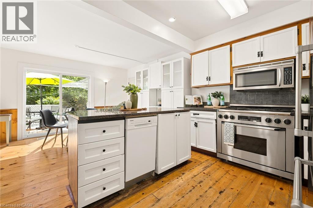 Kitchen featuring white cabinetry, stainless steel appliances, dark countertops, and wood-finish flooring - 351 Craigleith Drive, Waterloo, ON