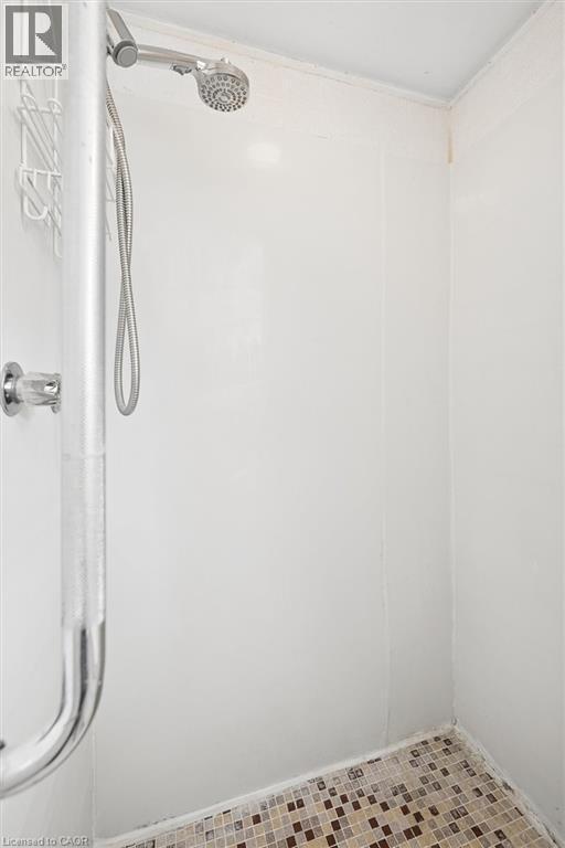White shower stall with mosaic tile flooring, a handheld showerhead, and a chrome grab bar - 351 Craigleith Drive, Waterloo, ON