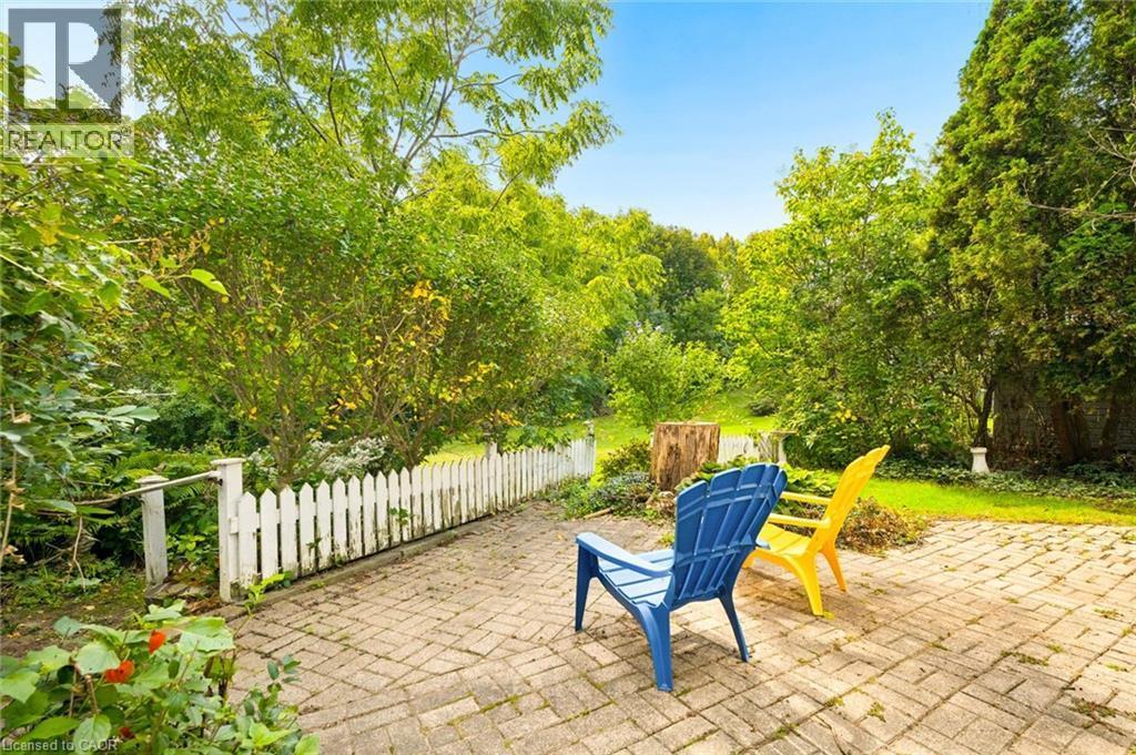 Brick paver patio with a white picket fence and abundant mature landscaping - 351 Craigleith Drive, Waterloo, ON