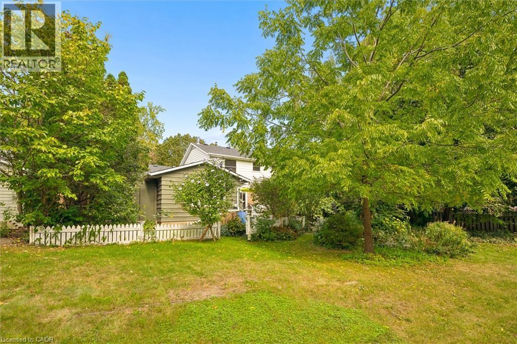 Expansive green lawn with mature trees and a white picket fence - 351 Craigleith Drive, Waterloo, ON