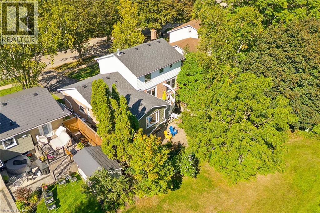 Expansive green backyard space with mature trees, a multi-level deck, and a built-in outdoor spa - 351 Craigleith Drive, Waterloo, ON
