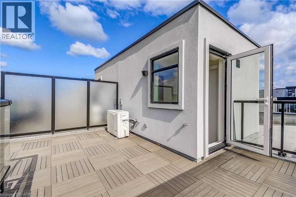 Rooftop deck featuring modular wood-finish flooring, a contemporary privacy screen, and an exterior door with a glass panel - 58 Windward Drive, Grimsby, ON