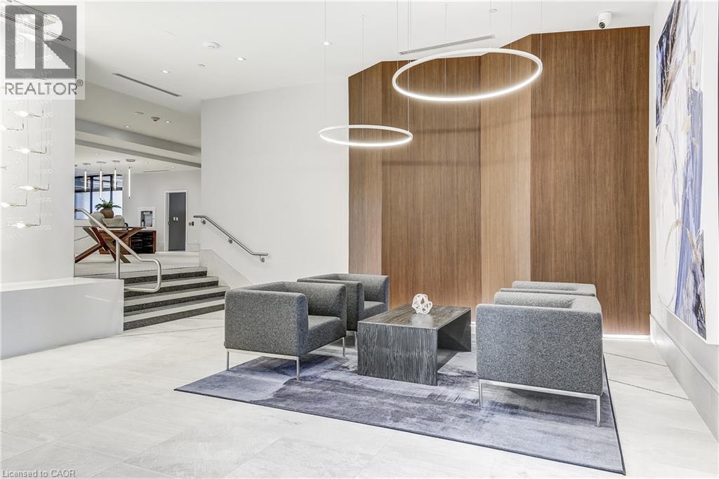 Lobby featuring wood-paneled accent wall, contemporary lighting fixtures, and a staircase with stainless steel handrails - 58 Windward Drive, Grimsby, ON
