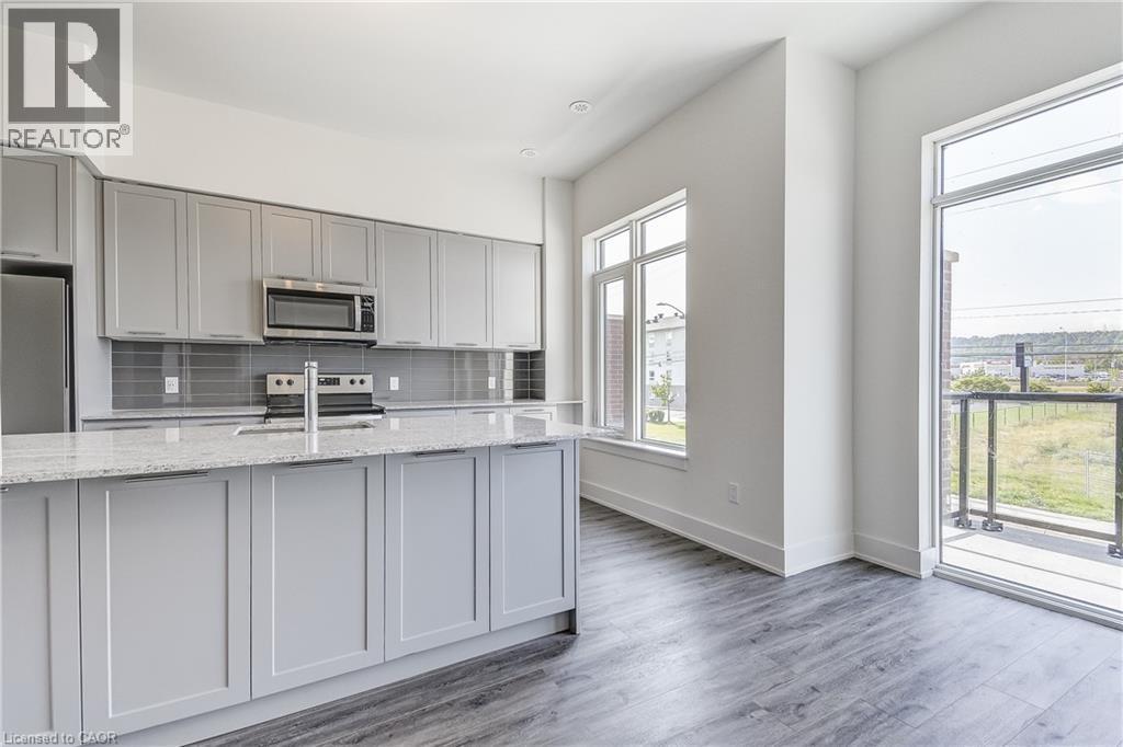 Kitchen featuring gray cabinetry, stainless steel appliances, a tile backsplash, light-toned countertops, and wood-finish flooring - 58 Windward Drive, Grimsby, ON