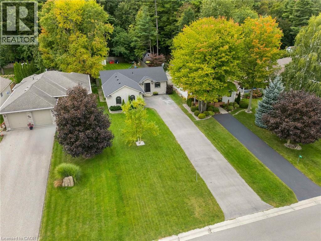 Property featuring a dark shingle roof, light-colored exterior, an attached garage, and a paved driveway - 53 Hawtrey Road, Delhi, ON